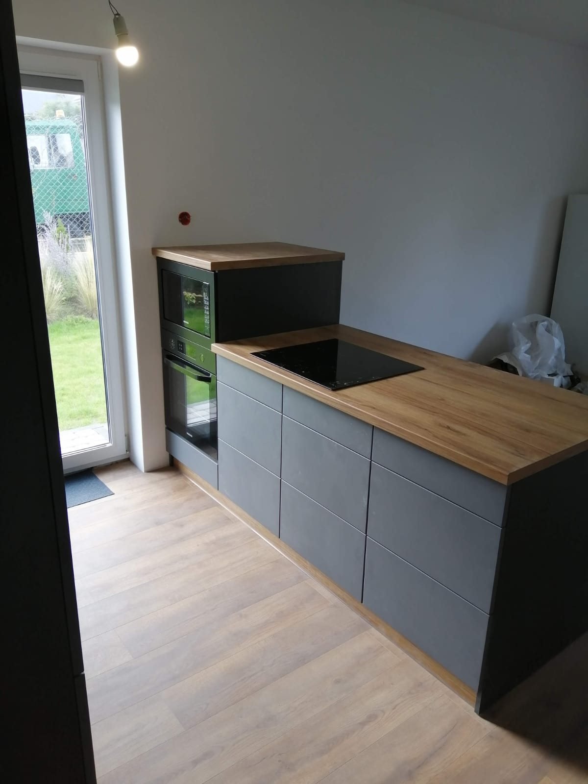 Kompakte Küche mit grauen Fronten und Holzplatte